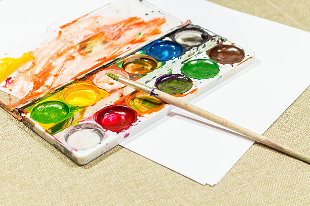 Used box with multi-colored paints and a brush for painting.