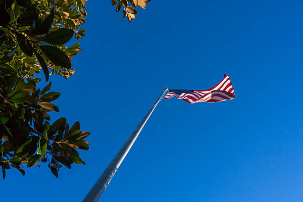 istock flagpole with American flag waving in clear sky 2221391022