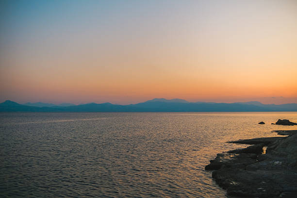 Rocky coastline with palm trees during sunset in Greece