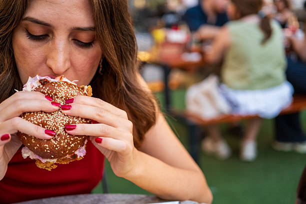 Woman Eating a Gourmet Burger at an Outdoor Restaurant