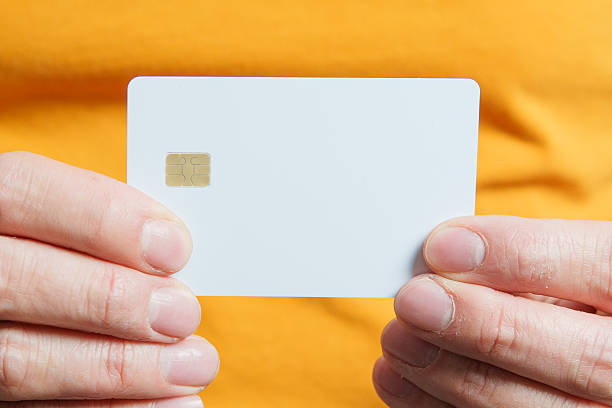 istock Hands holding white credit card with chip on orange background 2221399013