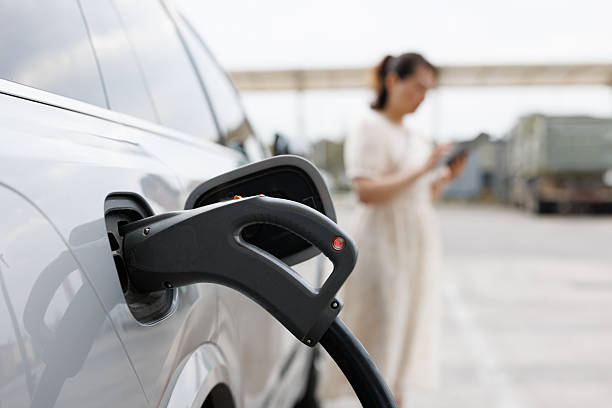 istock asian woman using mobile phone while charging electric car 2221401196