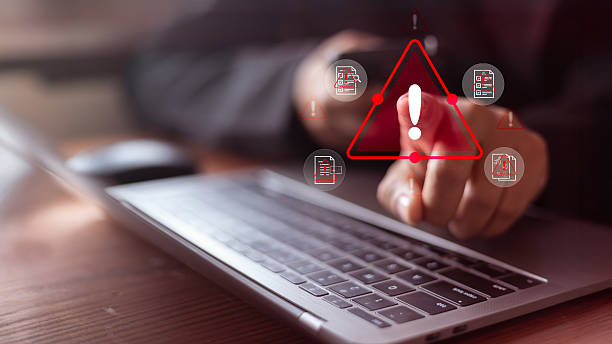 istock Cybersecurity warning concept with user pointing at a red alert icon on a laptop. Data breach risk, 2221409568