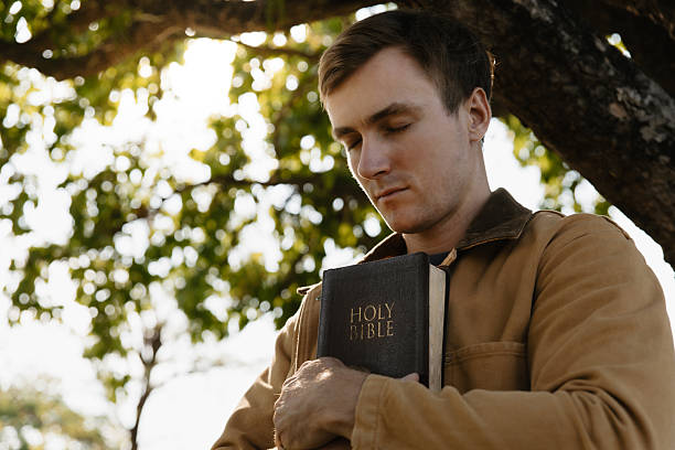 istock Young man holding a Bible and praying for god. 2221415006
