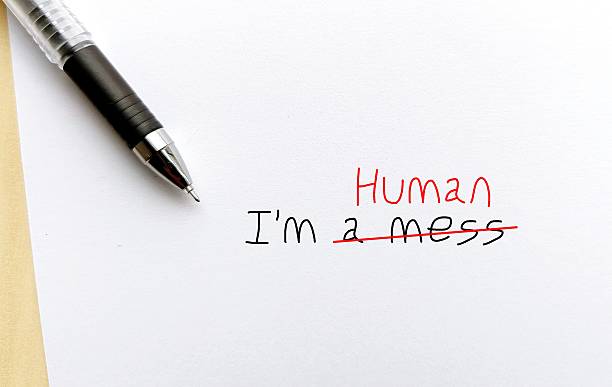 istock Pen on note paper with text written I AM A MESS, changed to I AM HUMAN - to overcome negative self talk or inner voice critic, change to positive thought to boost self esteem 2221419980