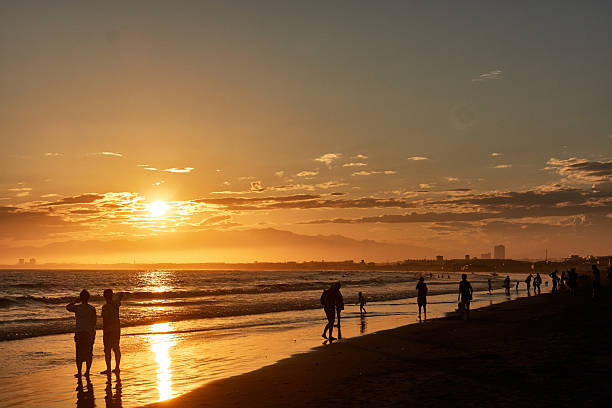 istock Scenic view of beach with people standing against dramtic sky during sunset 2221425090