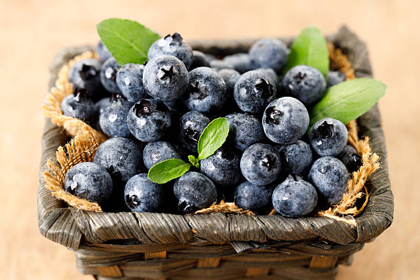 istock Ripe blueberries in wicker basket on wooden table. 2221425302