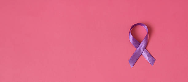 istock Purple ribbon lying on pink background symbolizing support for many important causes 2221436038
