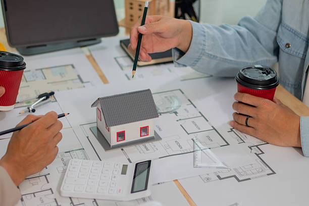 istock Architect and businessman discussing interior mansion plans using pencils and models at desk, including real estate purchase planning with leaders, marketing and engineering insights. 2221438748
