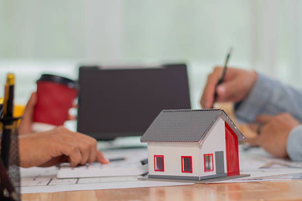 istock Architect and businessman discussing interior mansion plans using pencils and models at desk, including real estate purchase planning with leaders, marketing and engineering insights. 2221439116