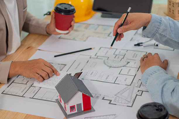 istock Architect and businessman discussing interior mansion plans using pencils and models at desk, including real estate purchase planning with leaders, marketing and engineering insights. 2221439123