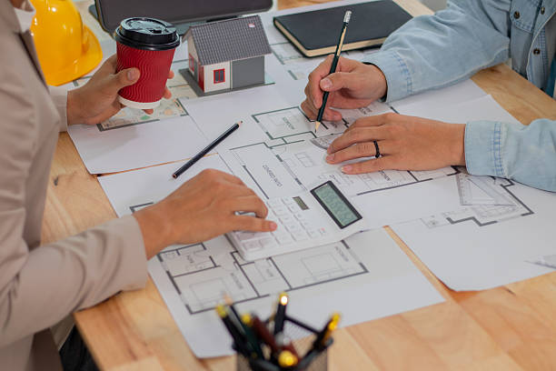 istock Architect and businessman discussing interior mansion plans using pencils and models at desk, including real estate purchase planning with leaders, marketing and engineering insights. 2221439125