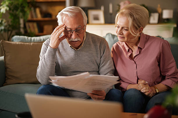 istock Worried senior couple reading documents at home on sofa 2221441322