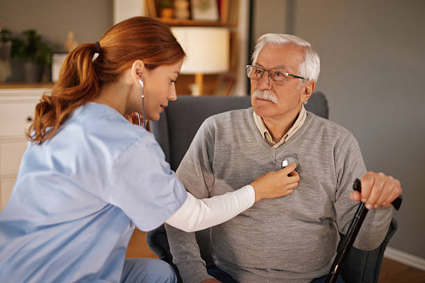 istock Young nurse visiting senior man at home using stethoscope 2221442556