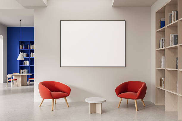 istock Blank poster mockup in modern interior with red chairs, bookshelf, and round table in soft light for clean design presentation or advertising template. 3D Rendering 2221443903