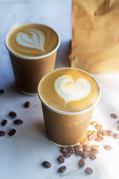 istock Hot latte coffee in take away paper cup on white marble table with roasted coffee beans. 2221452058