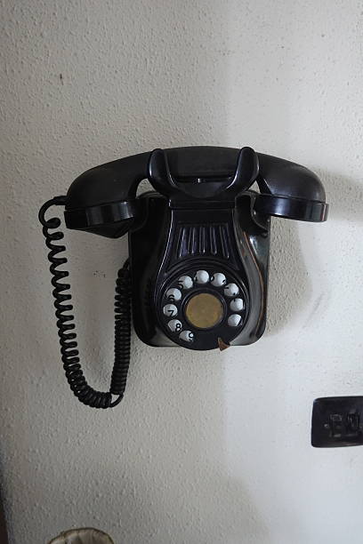 istock Old black rotary phone hanging on white wall 2221454742