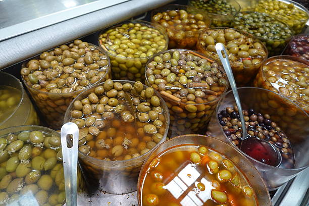 Various types of pickled olives, displayed in transparent containers, creating a colorful and flavorful presentation at a market stall