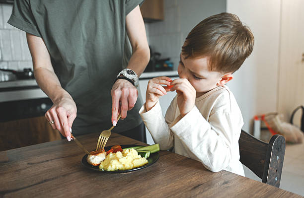 istock mother feeds lunch to her little son 2221456893