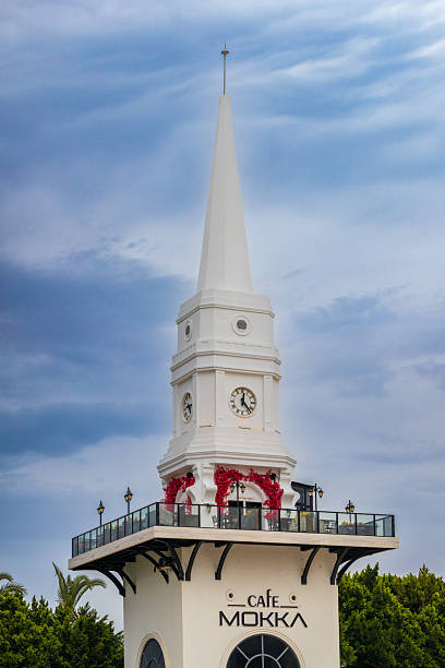 Kemer, Antalya province, Turkey - May 10, 2025: The spire of the Clock Tower or White Tower against blue sky, Kemer. Symbol of Kemer. Located at the intersection of boulevards - Ataturk and Dortyol