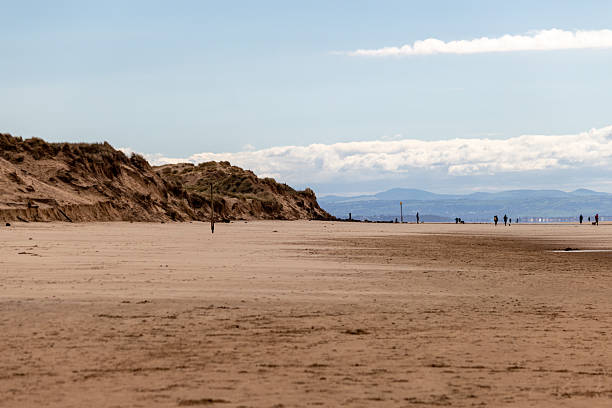 istock A sandy beach stretches towards a distant horizon beneath a bright sky. 2221460885