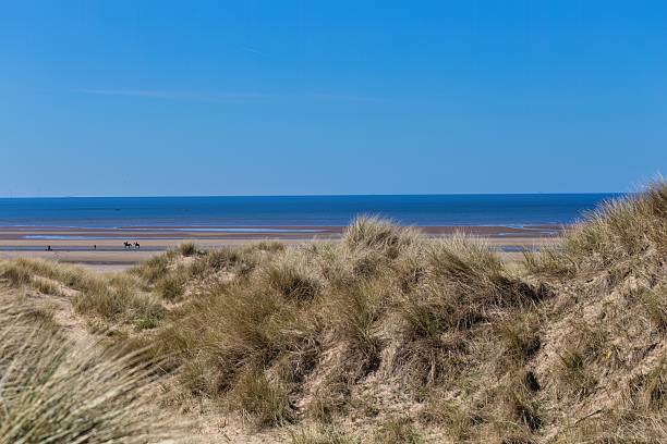 istock Sandy dunes lead to a beach with a clear blue sky above. 2221462413