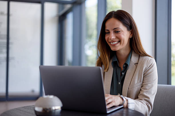 istock Professional woman working on laptop, smiling confidently in modern, sunlit workspace, embodying workplace success and productivity 2221465071