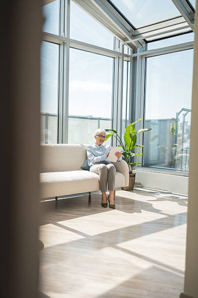 istock Mature woman reading in a bright modern conservatory with natural sunlight 2221467431