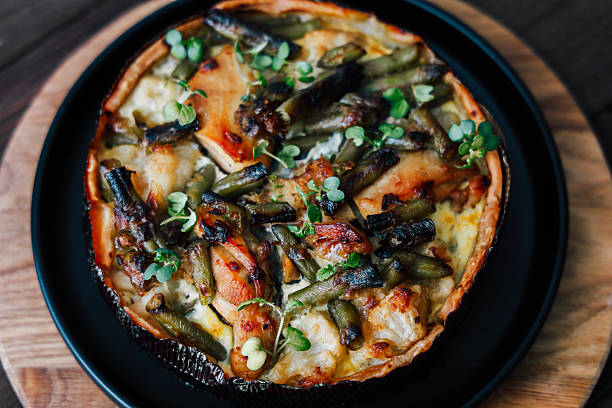 Freshly baked vegetable quiche showcasing a variety of greens arranged beautifully with herbs served warm on a wooden board.