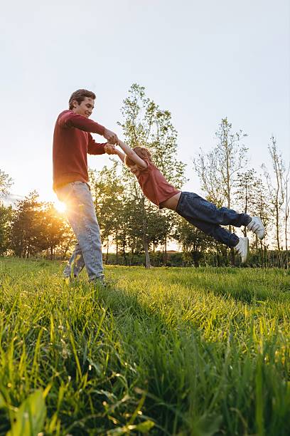 istock Father spinning son in park at sunset 2221478032