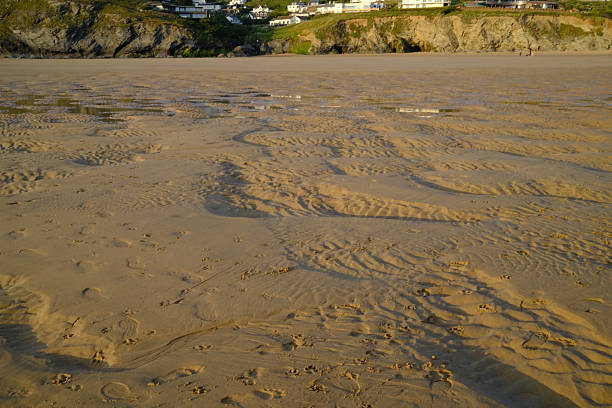 Patterns in the sand created by the tide, on a sunny evening with shadows showing the contours of the sand