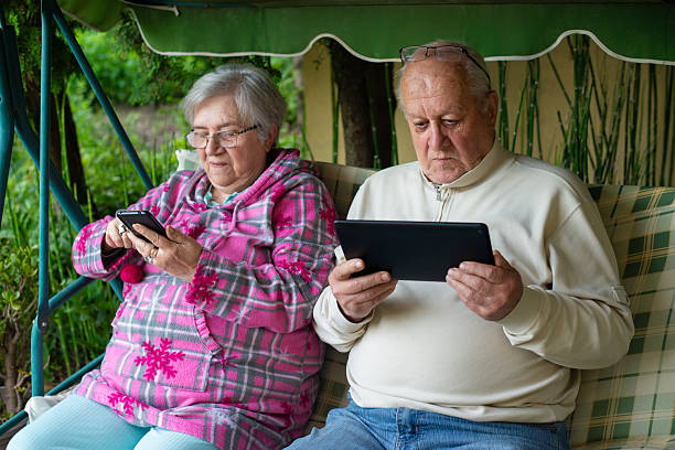 istock Senior couple using phone and tablet while sitting in their back yard 2221485093