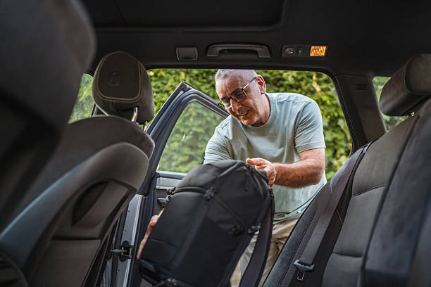 istock mature man pack luggage into car before road trip 2221485923