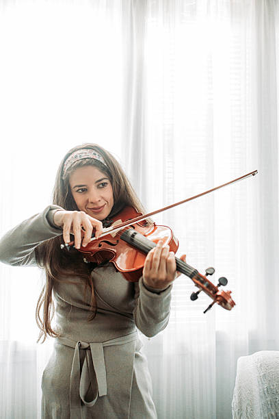 istock Young brunette girl play a violin at home, practice 2221486086
