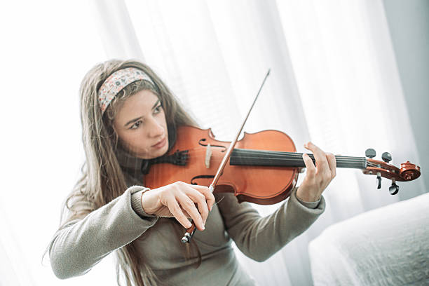istock Young brunette girl play a violin at home, practice 2221486155