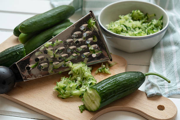 Grated and whole cucumber on cutting board