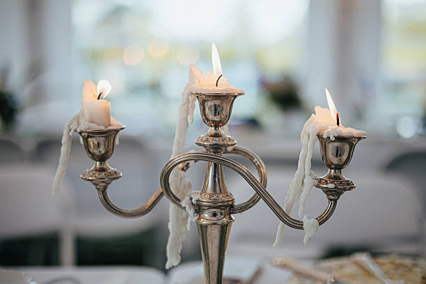 A trio of lit candles on a silver candelabra creates a warm and inviting ambiance, set against a softly blurred background with subtle floral accents, evoking a sense of romance and elegance