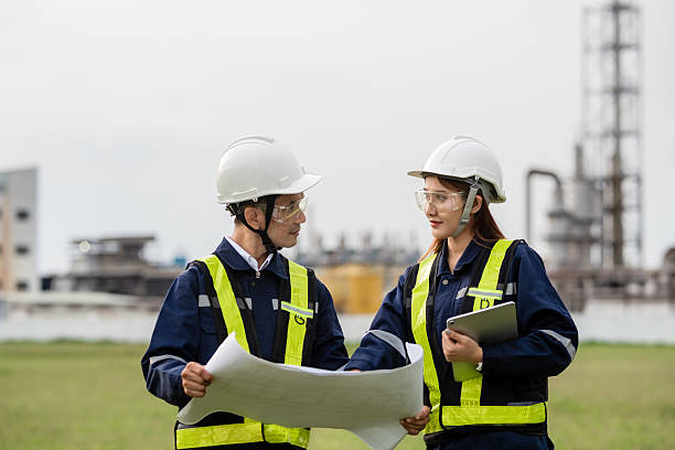 istock Two Engineers Happily Discussing a Project Plan with a Blueprint and Tablet. Two people wearing safety gear and holding papers 2221490850