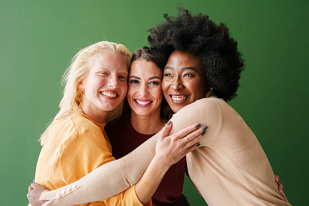 istock Three Multicultural Women Hugging Cheerfully Against a Vibrant Green Backdrop 2221495491