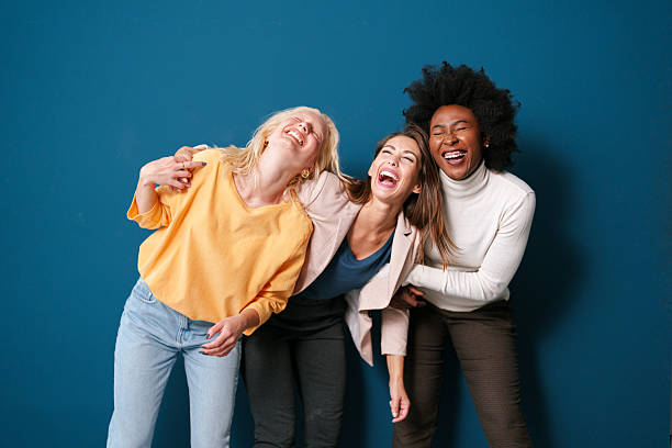 istock Three Multicultural Women Laughing Together in Casual Attire Against a Vibrant Blue Backdrop 2221495522