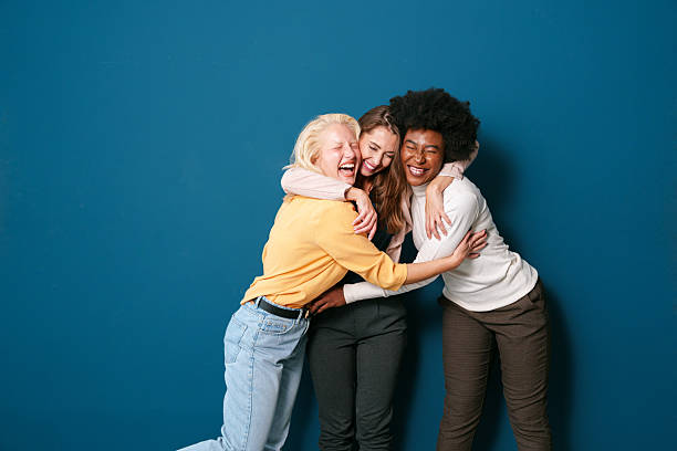 istock Three Diverse Friends Laughing Together in Casual Outfits Against Deep Blue Studio Background 2221495531