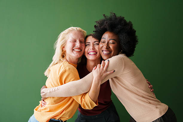 istock Three Multicultural Friends Sharing a Joyful Embrace Against a Vibrant Green Backdrop 2221495659