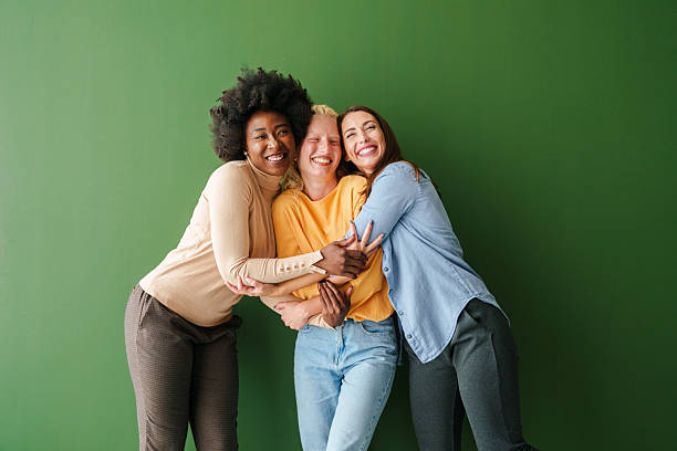 istock Three Multicultural Friends Smiling and Embracing Against a Vibrant Green Backdrop 2221495660
