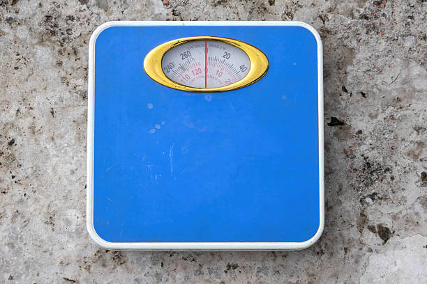 Blue analog weight scale on concrete surface. Top view of body weight machine displaying kilograms and pounds.