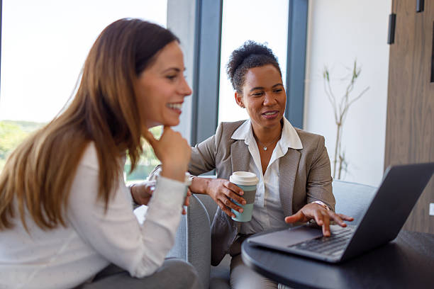 istock Professional women collaborating during coffee break, working together on laptop in modern office lounge area 2221506568