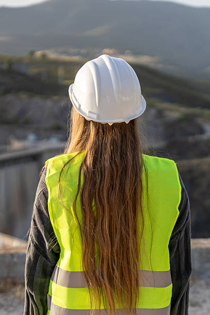 istock Female engineer inspecting construction site wearing safety vest and helmet 2221507500