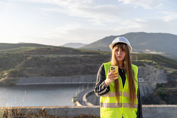 istock Female engineer using a smartphone near a dam, looking to the side 2221507533
