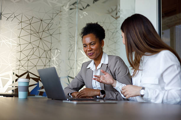 istock Two businesswomen are discussing a project, using a laptop in a modern office, showcasing teamwork and collaboration 2221508048