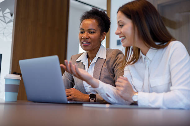 istock Professional women collaborating, analyzing project details on laptop screen in contemporary workspace 2221508388