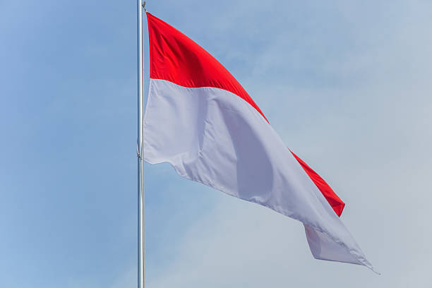 istock Indonesian Flag Waving Under Blue Sky 2221509865